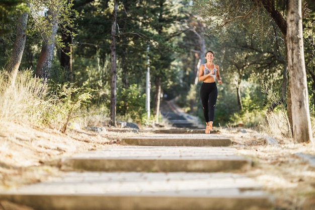 Mulheres de meia idade em forma estão correndo pela floresta de pinheiros perto da costa do mar e desfrutando no dia ensolarado de verão.