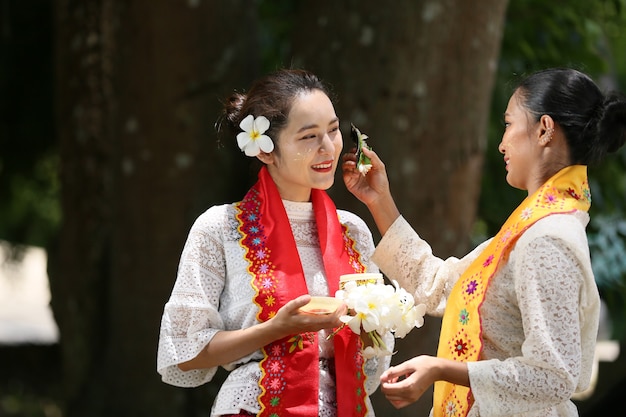 Mulheres de mianmar segurando flores em um templo. jovens do sudeste asiático com trajes tradicionais