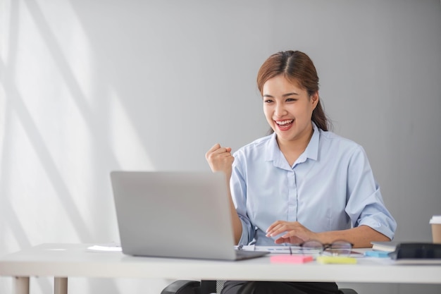 Mulheres de negócios asiáticas mostram uma expressão alegre de sucesso no trabalho sorrindo felizes com um computador portátil em um escritório moderno