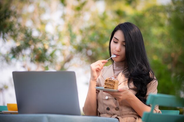 Mulheres de negócios asiáticos jovens está comendo bolo delicioso