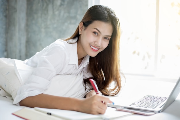 Mulheres de negócios asiáticos usando notebook e sorrindo feliz por trabalhar e escrever