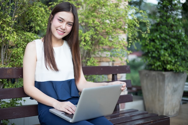 Mulheres de negócios asiáticos usando notebook e sorrindo feliz por trabalhar no exterior