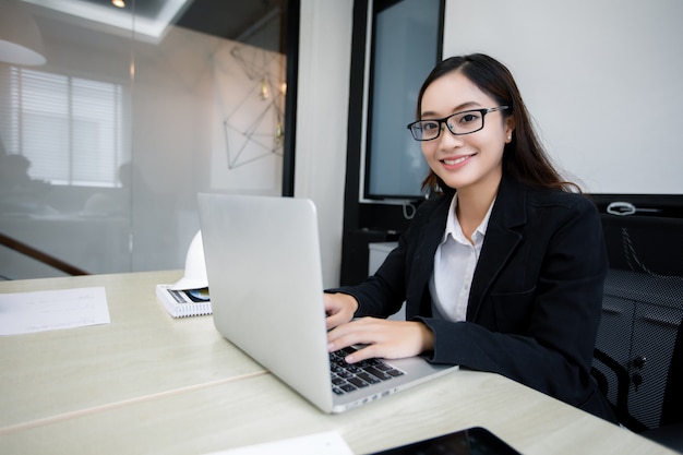 Mulheres de negócios asiáticos usando notebook e sorrindo feliz por trabalhar