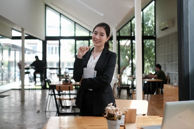 Mulheres de negócios atraentes em pé e sorrindo para a câmera na sala de reuniões.