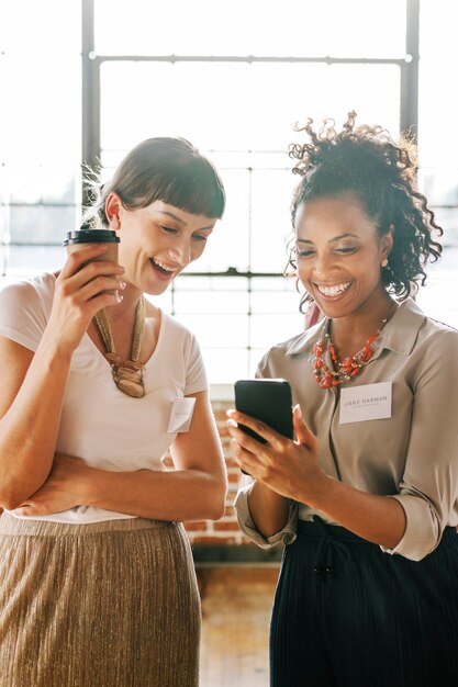 Mulheres de negócios compartilhando conteúdo online de um telefone