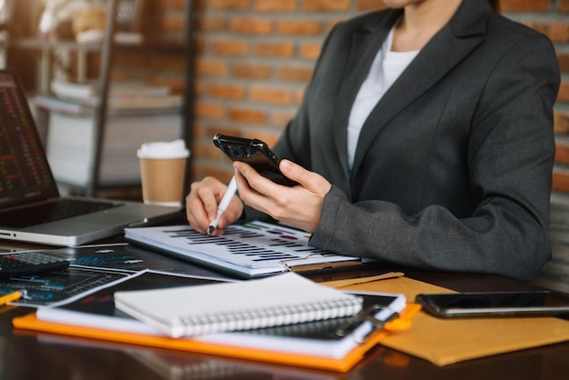 Mulheres de negócios de conceitos de negócios trabalhando na área de trabalho com smartphones e folhas de dados na mesa