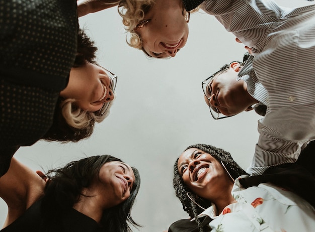 Mulheres de negócios diversificadas e felizes amontoadas no escritório