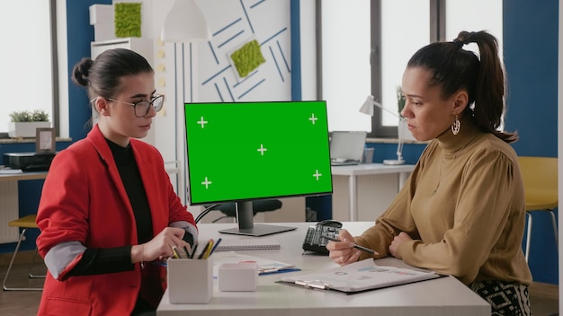 Mulheres de negócios fazendo trabalho em equipe no computador com tela verde, trabalhando com espaço de cópia simulada no modelo de chave cromática isolado e fundo em branco. Greenscreen no escritório de inicialização.