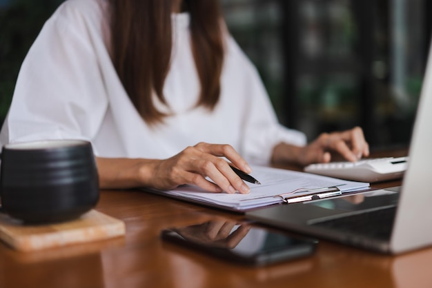 Mulheres de negócios que usam calculadora para verificar documentos financeiros enquanto trabalham fora do escritório