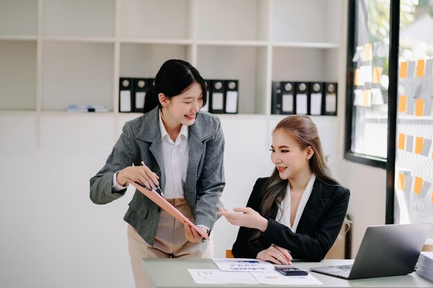 Foto mulheres de negócios trabalham e discutem seus planos de negócio uma funcionária humana explica e mostra ao seu colega o papel de resultados em um escritório moderno