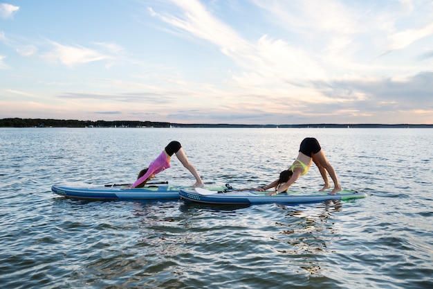 Foto mulheres de tiro completo fazendo ioga em paddleboards