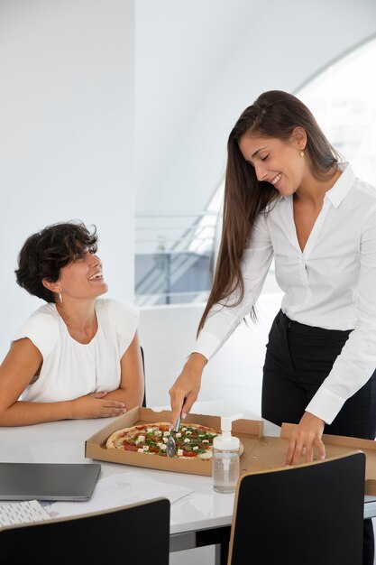 Mulheres de tiro médio com pizza