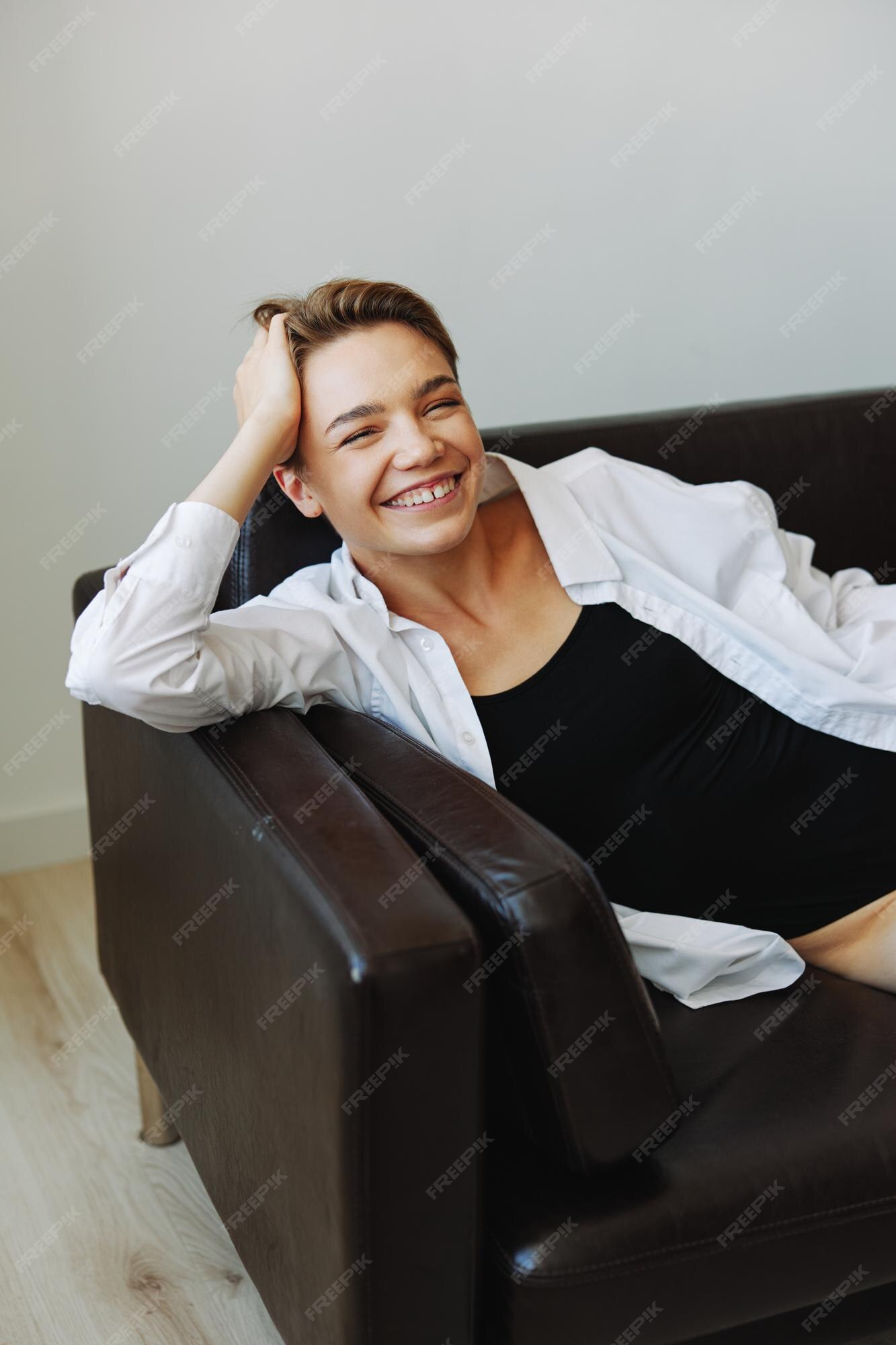 Mulheres deitadas em casa no retrato do sofá com um corte de cabelo curto  em uma camisa branca sorriem depressão nas férias em casa de adolescentes