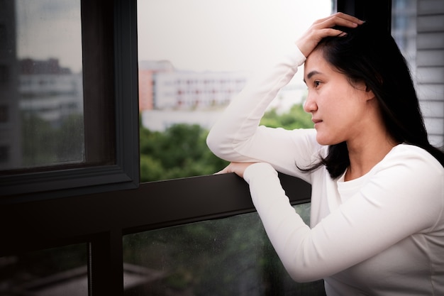 Mulheres deprimidas sentado perto da janela, sozinha, tristeza, conceito emocional