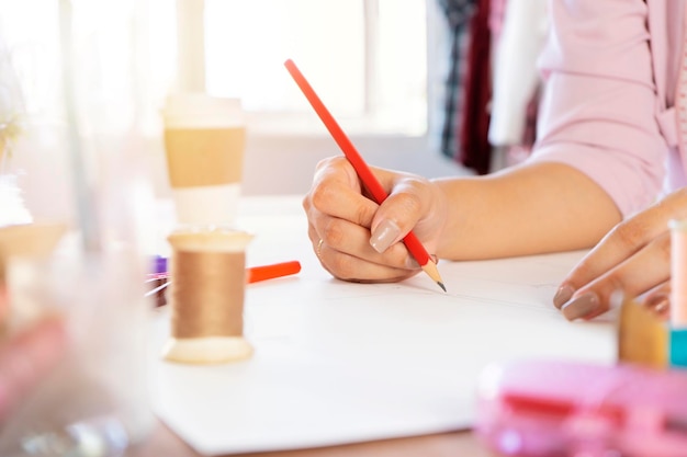 Mulheres designers asiáticas estão usando lápis para projetar obras em papel o dispositivo de costura é colocado