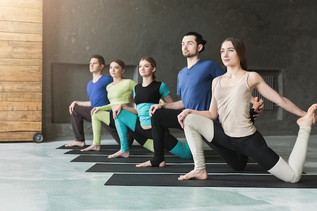 Mulheres e homens na aula de ioga, alongamento de pose de sereia. Estilo de vida saudável no clube de fitness, copie o espaço