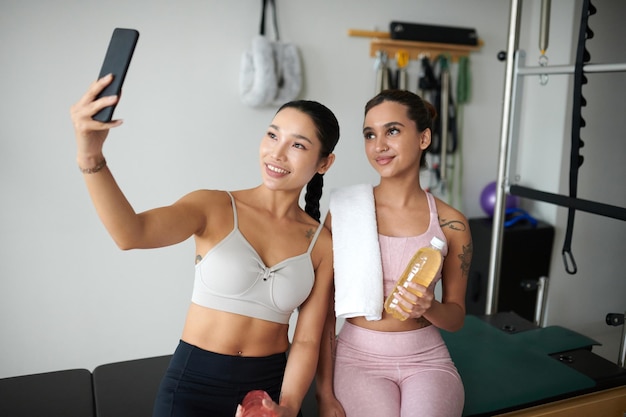 Foto mulheres em forma a tirar selfies no ginásio.