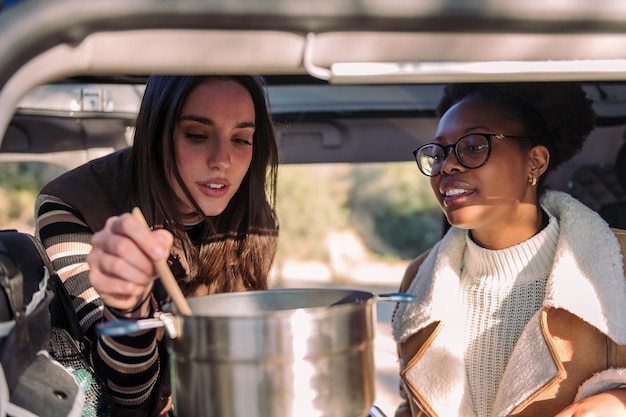 Mulheres em uma viagem viajam cozinhando em van de campista