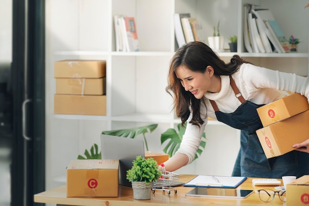 Mulheres empresárias Small Business SME Trabalho independente em casa, usando laptops para checagem comercial, marketing online, caixas de embalagem, conceito de vendedores SME, vendas online.