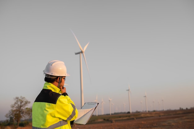 Mulheres engenheiras trabalhando e segurando o relatório na estação geradora de energia da fazenda de turbinas eólicas na montanhaTailândia