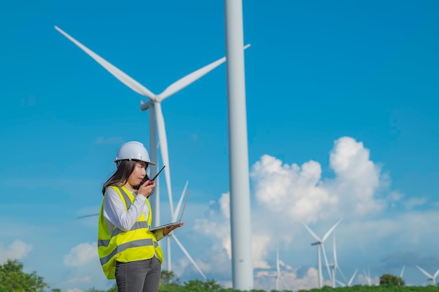 Mulheres engenheiras trabalhando e segurando o relatório na estação geradora de energia da fazenda de turbinas eólicas na montanhaTailândia