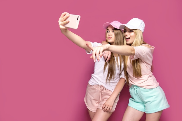 Mulheres esportivas tirando selfie na parede rosa