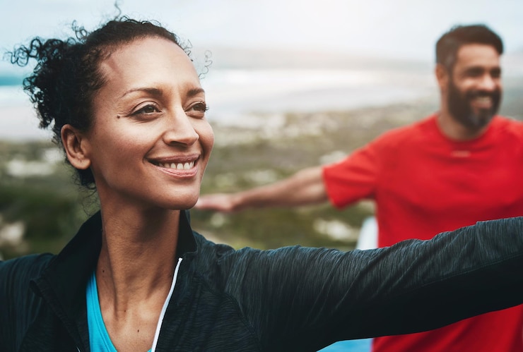 Foto mulheres esticando e braços para ioga ao ar livre com aquecimento pilates e atividade matinal para flexibilidade com sorriso pessoas exercitando e trabalho em equipe para fitness pelo oceano com bem-estar feliz e ativo