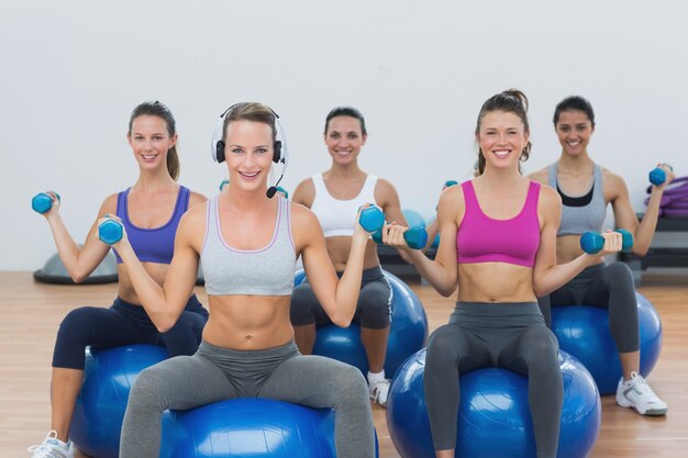 Mulheres exercitando com dumbbells em bolas de fitness