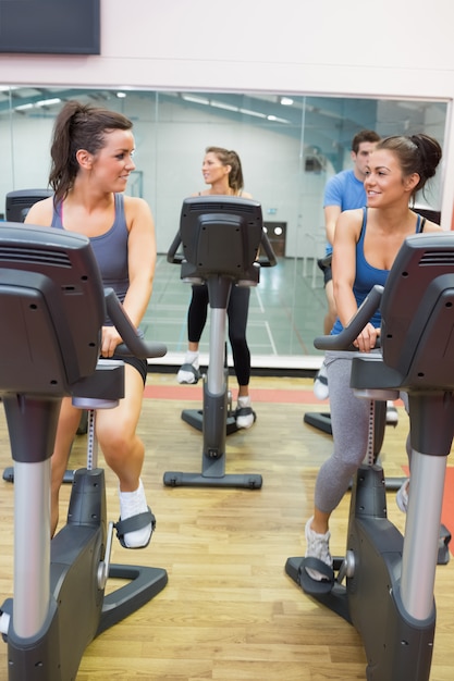 Mulheres, falando, enquanto, treinamento, ligado, bicicleta exercício