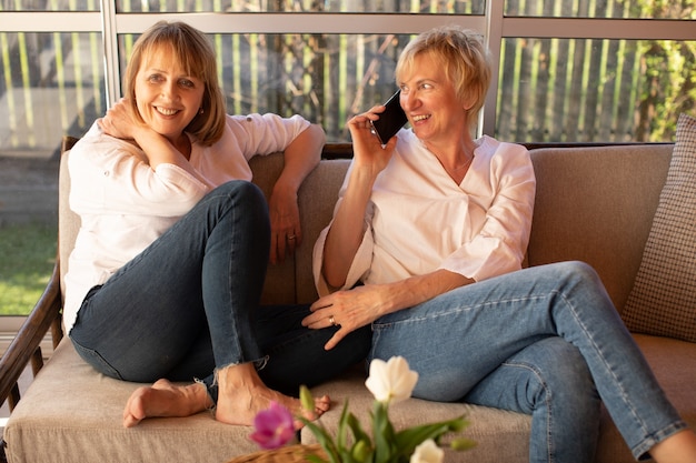 Mulheres fazem pedidos online na loja online enquanto estão sentadas na varanda de uma casa de madeira usando um smartphone