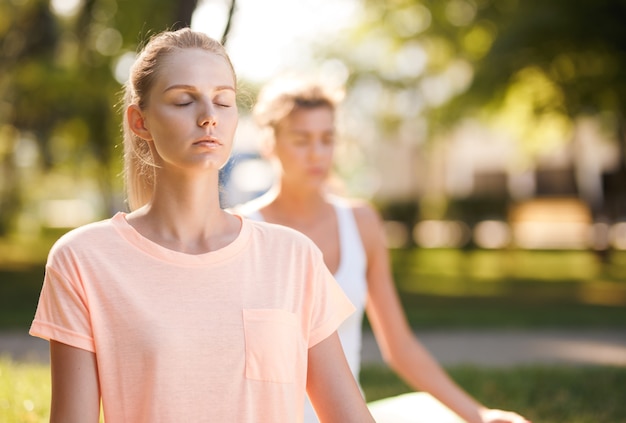 Mulheres fazendo ioga ao ar livre ao nascer do sol. Meditação matinal.