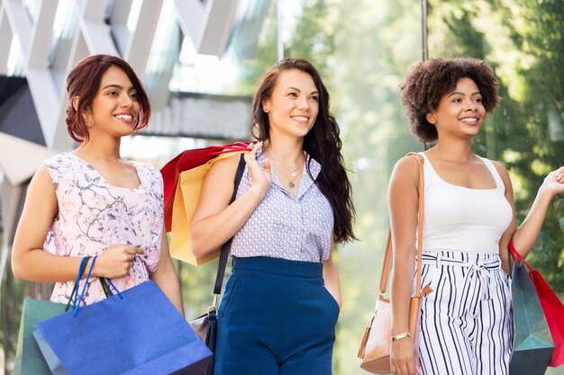 mulheres felizes com sacos de compras a caminhar pela cidade