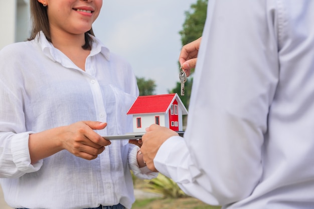 Mulheres felizes em uma nova casa comprando imóveis, mão segurando um sorriso de casa