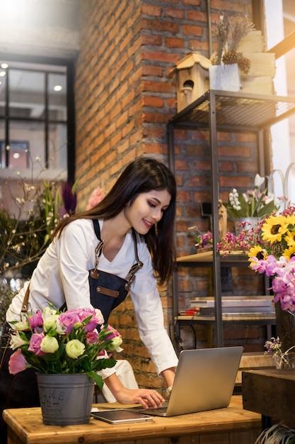 Foto mulheres florista procurando laptop tem ordem no balcão de sua loja de flores