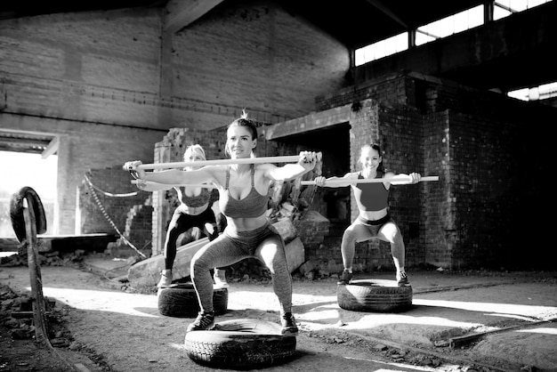 Mulheres fortes se exercitando em um hangar abandonado. treinamento feminino da aptidão do grupo. foto em preto e branco.