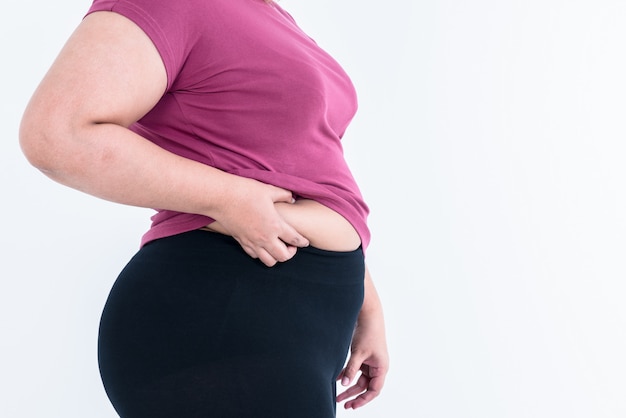 Foto mulheres gordas usando as duas mãos para segurar o excesso de gordura na área da cintura