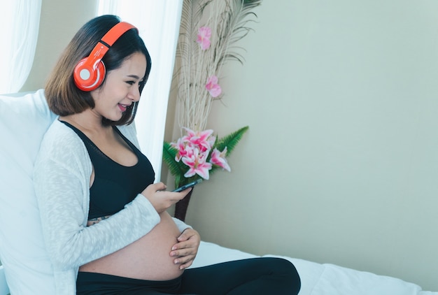 Foto mulheres grávidas ouvem música e tocam phones.happily