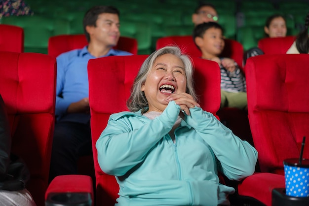 Mulheres idosas asiáticas ficam felizes assistindo filmes no cinema segurando pipoca nas mãos