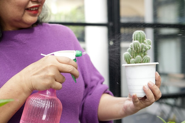 Mulheres idosas asiáticas vivem em casa, ela está regando as árvores Feliz em plantar uma árvore dando-lhe relaxamento e boa saúde O conceito de viver para os idosos na aposentadoria