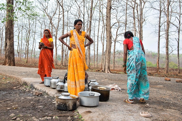 Mulheres indianas rurais carregam água em suas cabeças em potes tradicionais de bomba manual todos os dias Mulheres caminham alguns quilômetros para obtê-la devido à seca