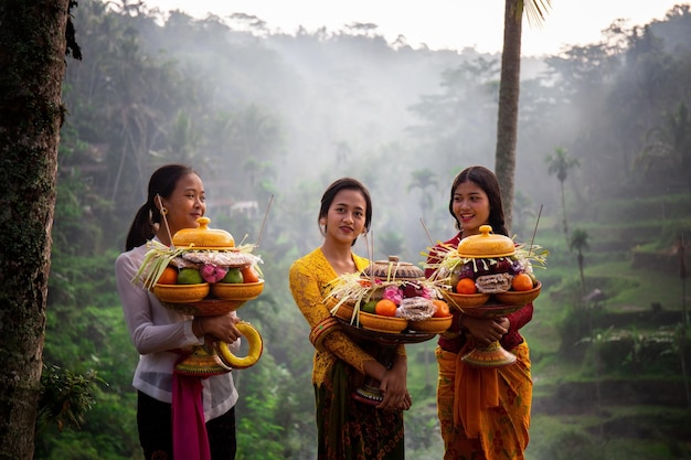 Mulheres indonésias em roupas tradicionais amarelas e vermelhas perto de campos de arroz em Ubud