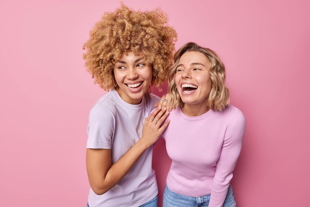 Mulheres jovens alegres e felizes riem alegremente vestidas com roupas casuais percebem algo engraçado risos expressam positivamente emoções positivas isoladas sobre fundo rosa Sentimentos humanos autênticos