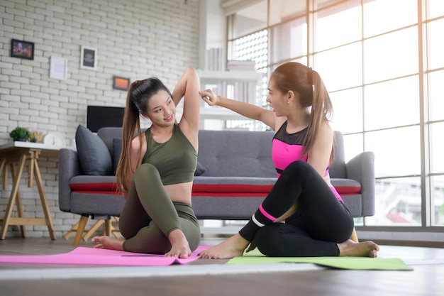 Mulheres jovens amigas praticando ioga em casa usando telefone inteligente via aula online