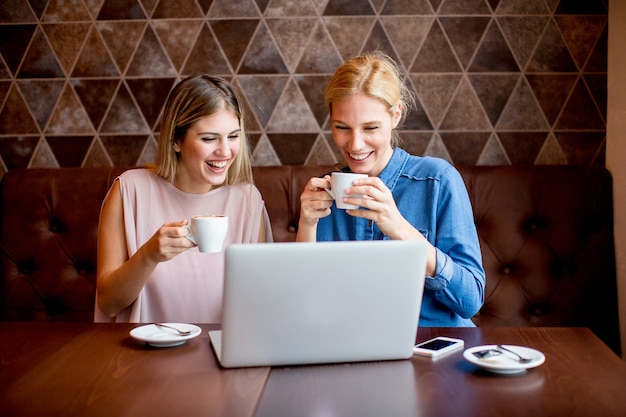 Mulheres jovens, com, laptop, sentando, pela tabela, em, café