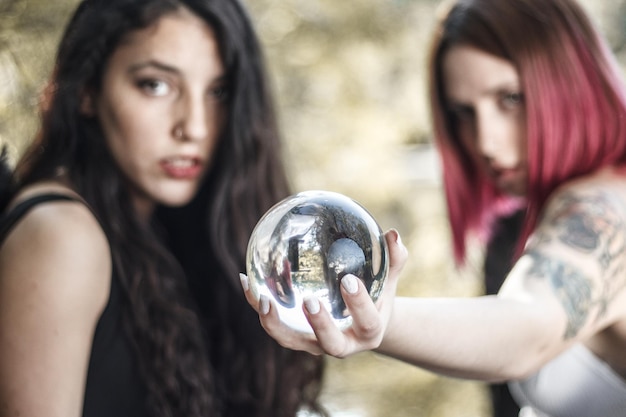 Mulheres jovens com uma bola de cristal na floresta