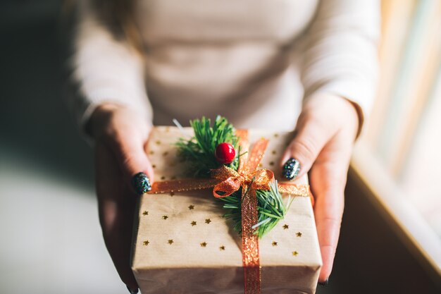 Mulheres jovens com unhas de glitter segurando a caixa de presente de natal