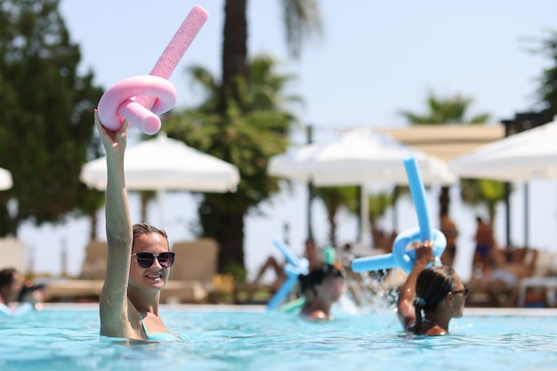 Mulheres jovens durante aulas de hidroginástica em esportes de piscina de hotel