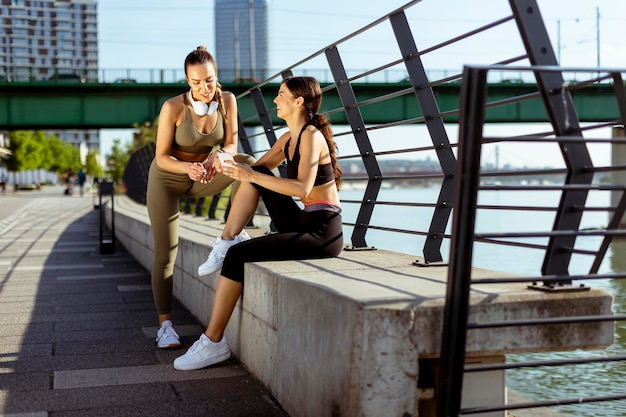 Mulheres jovens em roupas esportivas olhando para o celular após o treinamento físico