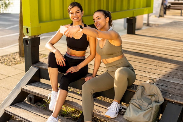 Mulheres jovens em roupas esportivas tomando selfie com telefone celular após treinamento físico