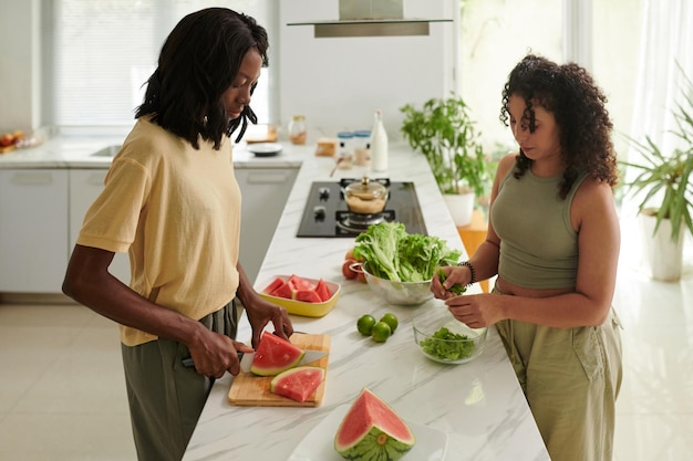 Mulheres jovens fazendo um jantar delicioso e saudável no balcão da cozinha